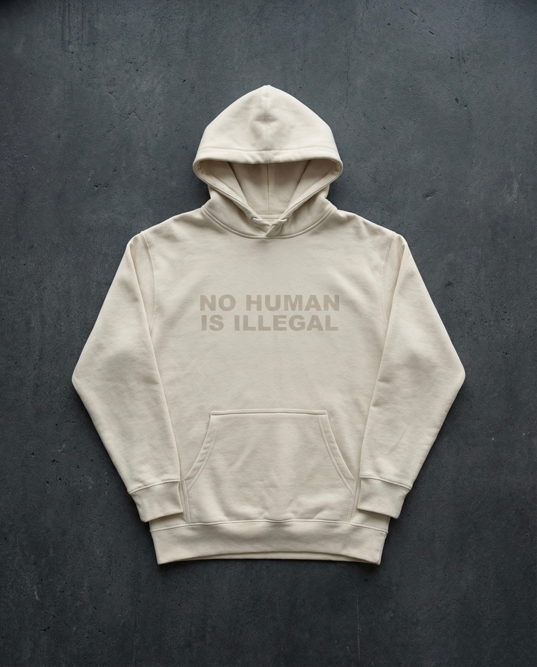 NO HUMAN IS ILLEGAL Shadow Edition Hoodie concrete background in bone | BAD BUREAU 