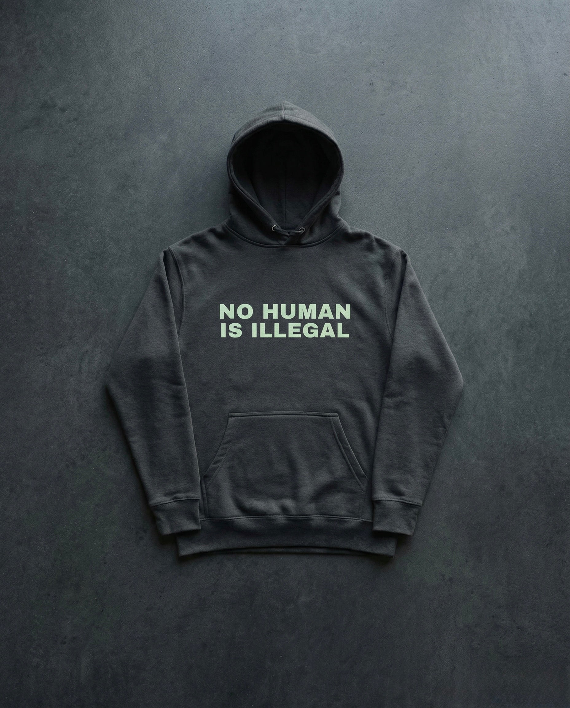 NO HUMAN IS ILLEGAL Hoodie Concrete Background in Charcoal | BAD BUREAU 